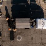 Vista aérea de trabajadores realizando labores de bacheo en una vialidad con apoyo de un camión de obra