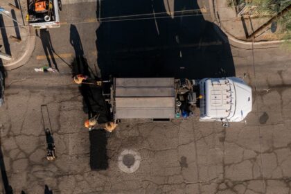 Vista aérea de trabajadores realizando labores de bacheo en una vialidad con apoyo de un camión de obra