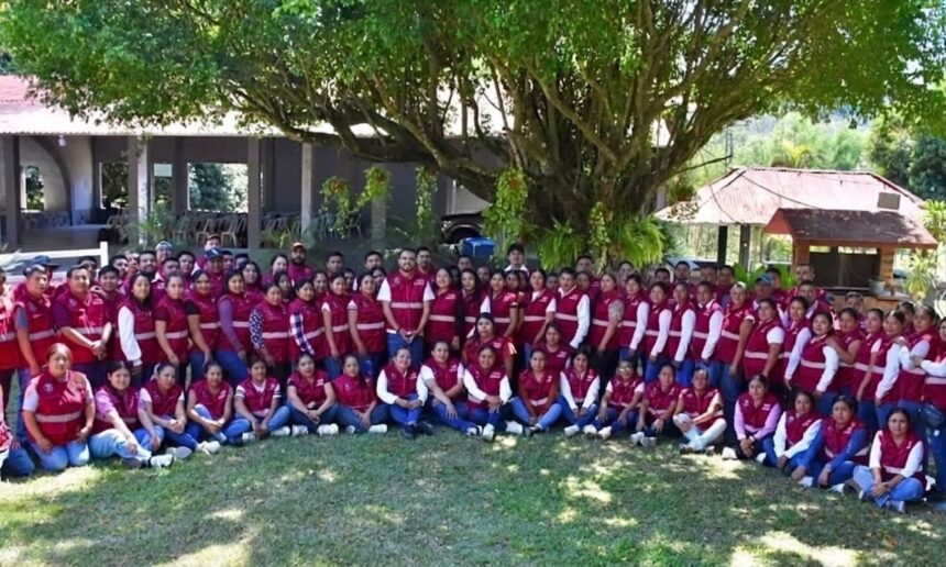 Grupo de personas con chalecos guinda reunidas al aire libre bajo un árbol