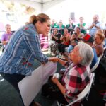 Marina del Pilar Ávila Olmeda saluda a una mujer adulta mayor durante una jornada de apoyos en Baja California.