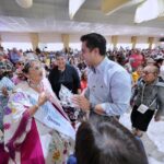 Felifer Macías saluda a una asistente durante la celebración del Día de las Personas Adultas Mayores Baile de Plata en Querétaro.