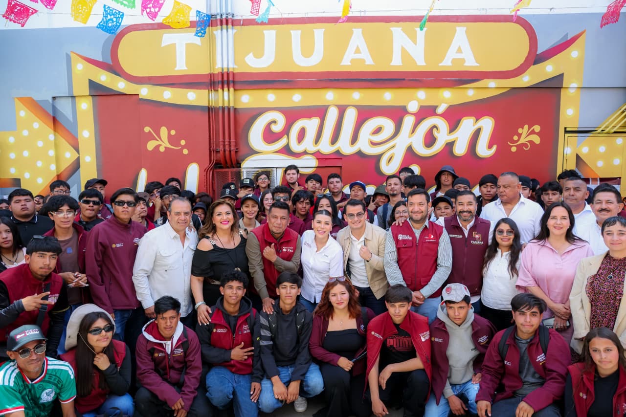 Autoridades y jóvenes participan en una actividad del Proyecto Tijuana: Ruta de la Paz frente a un mural en Tijuana.