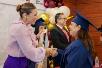 Marina del Pilar Avila Olmeda saluda a una mujer graduada durante un acto de certificación educativa en Baja California