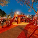 Parque iluminado con área de juegos y familias durante la noche en Guadalajara