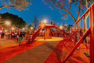 Parque iluminado con área de juegos y familias durante la noche en Guadalajara