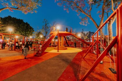 Parque iluminado con área de juegos y familias durante la noche en Guadalajara