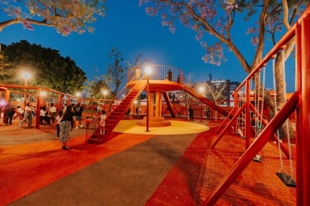 Parque iluminado con área de juegos y familias durante la noche en Guadalajara