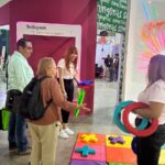Personas participan en una actividad del Instituto de las Mujeres en un módulo instalado en la Feria Nacional Potosina.