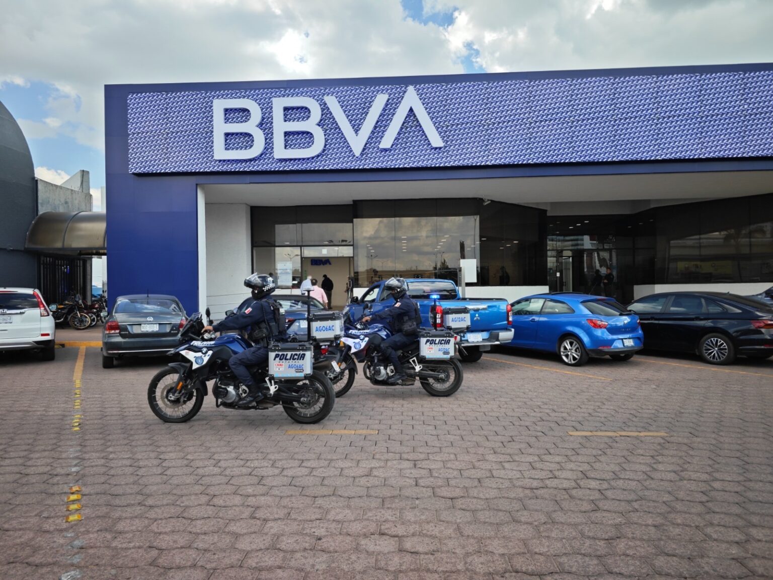 Elementos de la Policía Estatal de Aguascalientes en motocicletas frente a una sucursal bancaria.