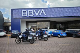 Elementos de la Policía Estatal de Aguascalientes en motocicletas frente a una sucursal bancaria.