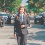 Presidenta municipal de Guadalajara durante una presentación sobre seguridad, con unidades y elementos policiales al fondo.
