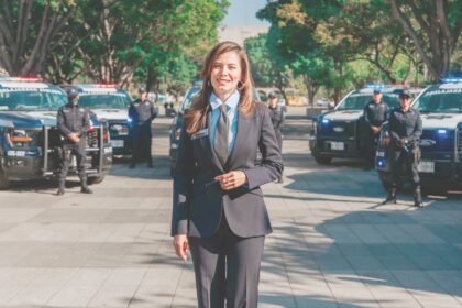 Presidenta municipal de Guadalajara durante una presentación sobre seguridad, con unidades y elementos policiales al fondo.