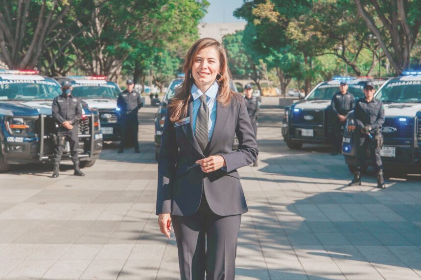 Presidenta municipal de Guadalajara durante una presentación sobre seguridad, con unidades y elementos policiales al fondo.