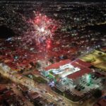 Vista aérea nocturna de Soledad de Graciano Sánchez durante un evento con fuegos artificiales y la Unidad Administrativa Municipal iluminada.