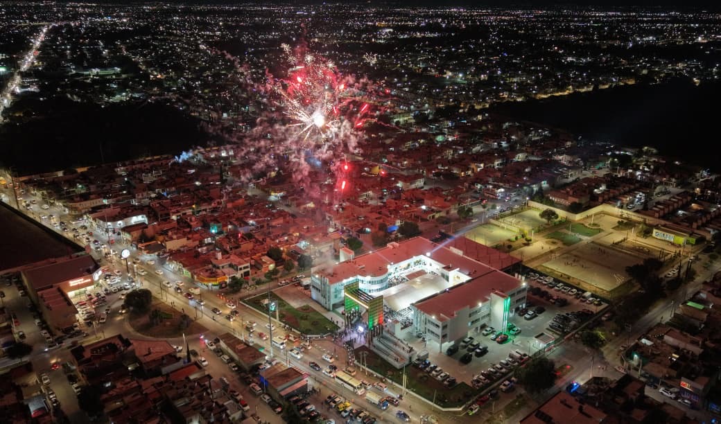 Vista aérea nocturna de Soledad de Graciano Sánchez durante un evento con fuegos artificiales y la Unidad Administrativa Municipal iluminada.