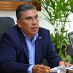 Hombre con traje oscuro y camisa azul durante una reunión de trabajo.
