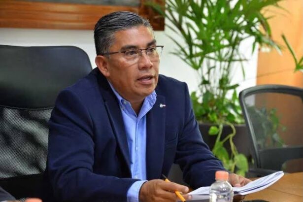 Hombre con traje oscuro y camisa azul durante una reunión de trabajo.