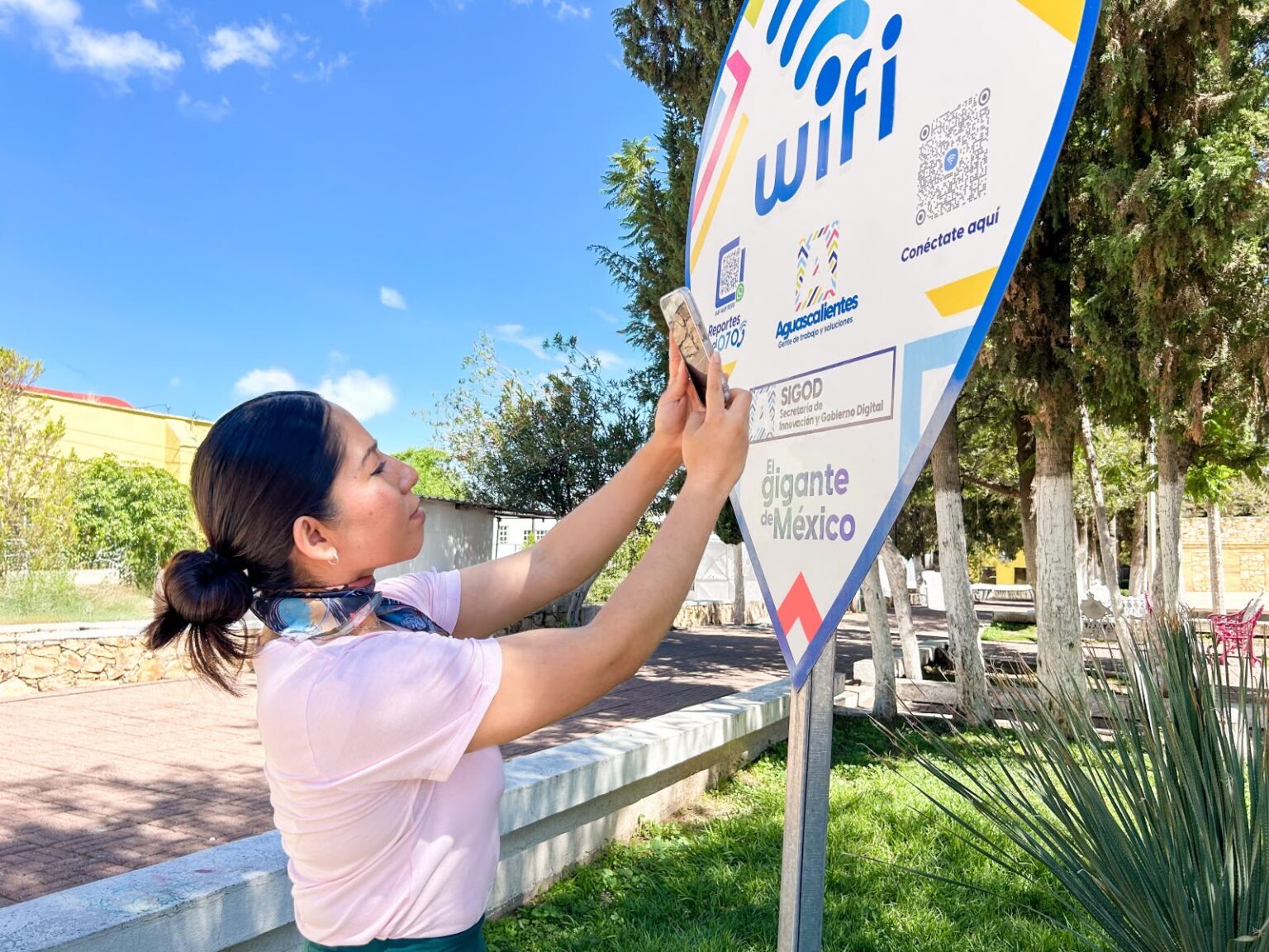 Persona escanea un código QR en un punto de conexión WiFi del Gobierno de Aguascalientes.