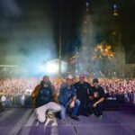 Integrantes de Plastilina Mosh y acompañantes posan sobre el escenario frente al público reunido en la Exedra de Aguascalientes durante el festival de aniversario.