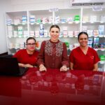 Tres mujeres posan en el mostrador de una Clínica del Bienestar, frente a estantes con medicamentos.