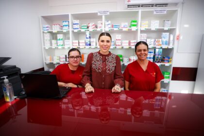 Tres mujeres posan en el mostrador de una Clínica del Bienestar, frente a estantes con medicamentos.
