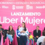 Una mujer habla ante el público durante el lanzamiento de Uber Mujeres en Aguascalientes, frente a un fondo rosa del evento.