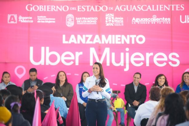 Una mujer habla ante el público durante el lanzamiento de Uber Mujeres en Aguascalientes, frente a un fondo rosa del evento.