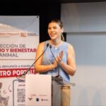Una mujer interviene ante micrófonos durante un foro sobre derecho y bienestar animal en Baja California, junto a un cartel informativo para denunciar maltrato.