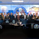 Delegación de visitantes y personal policial posan en el centro de monitoreo del Departamento de Policía de Winston-Salem, frente a pantallas y estaciones de trabajo