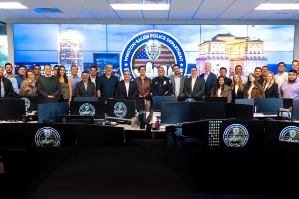 Delegación de visitantes y personal policial posan en el centro de monitoreo del Departamento de Policía de Winston-Salem, frente a pantallas y estaciones de trabajo