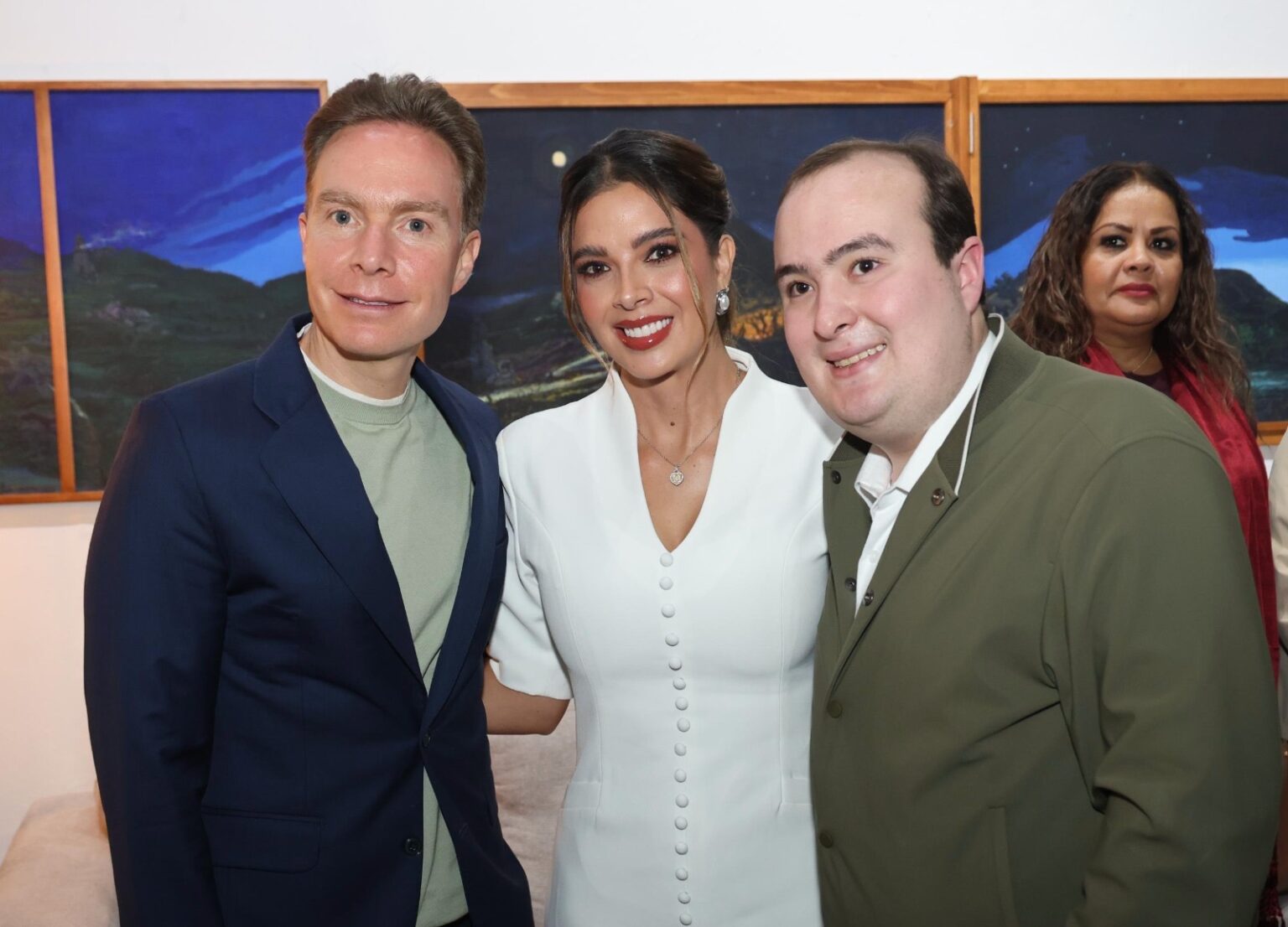 Tres personas posan para una fotografía durante un encuentro en un recinto interior