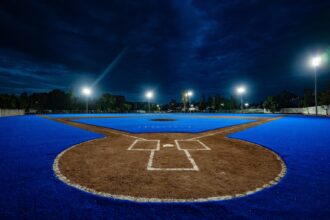 Campo de béisbol de la Unidad Deportiva Josefa Ortiz de Domínguez en Querétaro, con superficie azul e iluminación nocturna