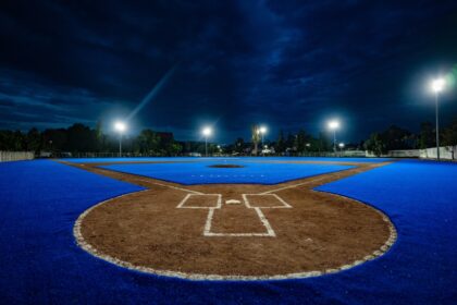 Campo de béisbol de la Unidad Deportiva Josefa Ortiz de Domínguez en Querétaro, con superficie azul e iluminación nocturna